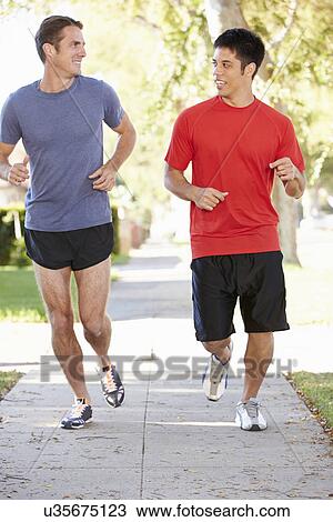 Stock Image - Two Male Runners Exercising On Suburban Street. Fotosearch