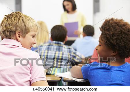 Stock Image - Two Pupils Talking In Class Together. Fotosearch
