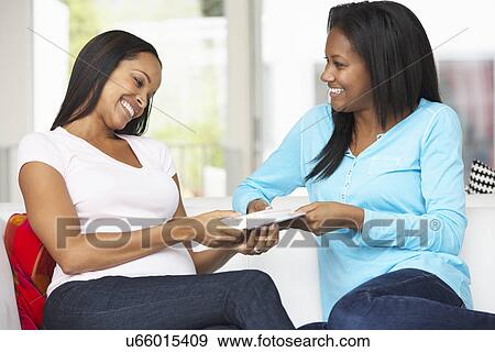 Two Women Sitting On Sofa Exchanging Gifts View Large Photo Image Stock Photo - Two Women Sitting On Sofa Exchanging Gifts. Fotosearch