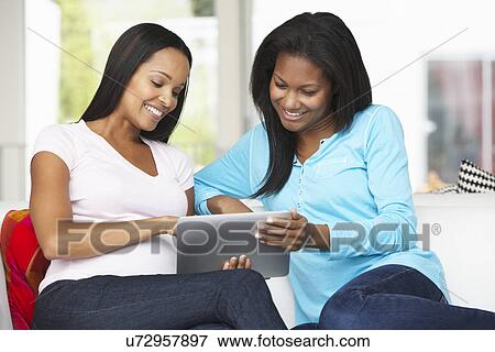 Stock Photo - Two Women Sitting On Sofa With Tablet Computer. Fotosearch