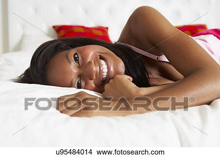 Picture - Woman Relaxing In Bed Wearing Pajamas. Fotosearch