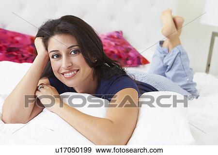 Stock Photo - Woman Relaxing In Bed Wearing Pajamas. Fotosearch