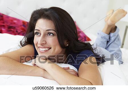 Stock Photograph - Woman Relaxing In Bed Wearing Pajamas. Fotosearch