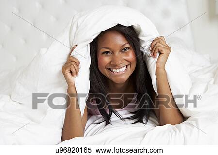 Stock Photography - Woman Relaxing In Bed Wearing Pajamas. Fotosearch