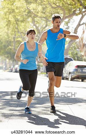 Picture - Woman Running Along Street With Personal Trainer. Fotosearch