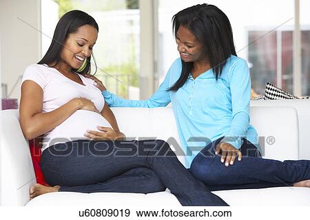 Stock Photo - Woman Visiting Pregnant Friend At Home. Fotosearch