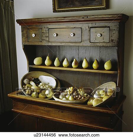 Stock Photograph - Antique wooden dry sink with row of stone pears and variety of carved stone fruit in wooden bowls. Fotosearch