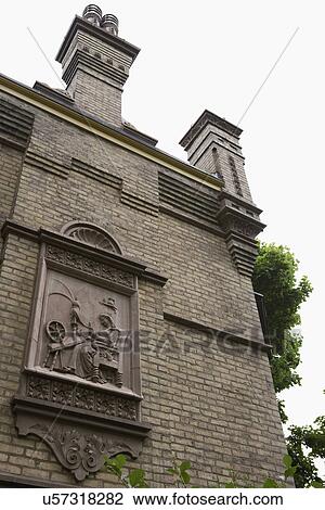 Stock Image - ARCHITECTURAL DETAIL EXTERIORS: Teutonic style, yellow - green Chicago brick, stepped gables, brick corbelling, terra cotta coping, bays, ornate chimney stacks, allegorical panels. Fotosearch