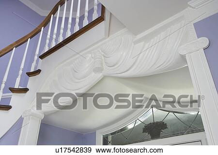 Stock Photo - Architectural detail: View of top section of passageway surround. Pilasters and columns. Stairway crosses over entryway. White woodwork and lavender walls.. Fotosearch