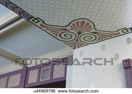 Stock Photograph -  ARCHITECTURAL TREATMENTS: Ceiling treatment: Aesthetic movement Victorian wallpaper, Neo classic style motifs, gold and terra cotta colors. Library in basement ceiling. Fotosearch