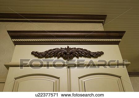 Stock Image - ARCHITECTURAL TRIM: Dark stained crown molding with yellow painted cabinets, wainscot ceiling, straight on view looking up. Fotosearch
