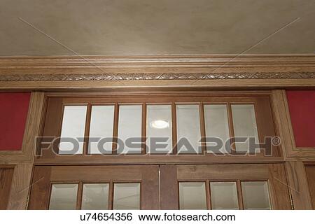 Stock Photograph - ARCHITECTURAL TRIM: Ornate crown molding red walls, transom above. Fotosearch