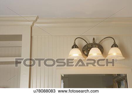 Stock Image - ARCHITECTURAL TRIM: soft painted wainscot, sconce above vanity mirror, cottage style simple clean lined. Fotosearch