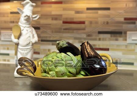 Stock Image - Artichokes and eggplant in bowl, Albuquerque, New Mexico, USA. Fotosearch