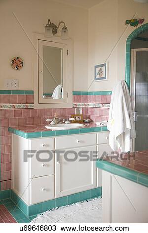 Stock Image - Bathroom sink and counter in pink and teal tiled bathroom; Carpinteria; California; USA. Fotosearch