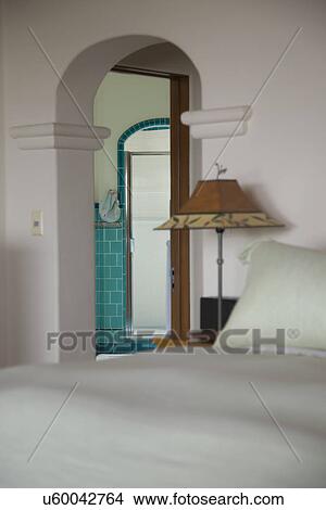 Picture - Bed side lamp and arched doorway in bedroom; Carpinteria; California; USA. Fotosearch