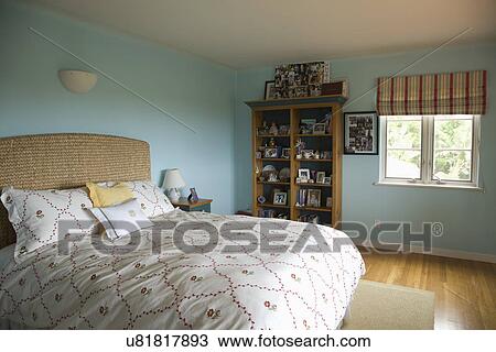 Stock Image - Bed with floral print comforter in blue bedroom; Carpinteria; California; USA. Fotosearch