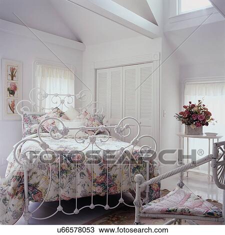 BEDROOM - All-white. Floral spread. White curlicue iron bed. Wicker, exposed beams, vaulted ceiling, pink floral arrangement, romantic cottage style, louvered doors, molding View Large Photo Image Stock Image - BEDROOM - All-white. Floral spread. White curlicue iron bed. Wicker, exposed beams, vaulted ceiling, pink floral arrangement, romantic cottage style, louvered doors, molding. Fotosearch