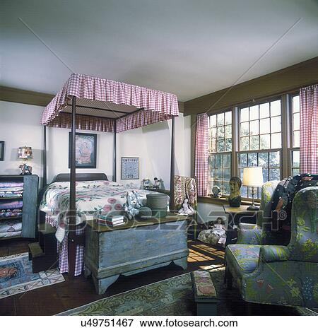 BEDROOM: Colonial girls room, checked canopy and curtains, antique weathered trunk with a bracket foot, wing chair with crewel fabric, quilts stacked in a weathered cabinet, various dolls, shaker boxes, View Large Photo Image Stock Photo - BEDROOM: Colonial girls room, checked canopy and curtains, antique weathered trunk with a bracket foot, wing chair with crewel fabric, quilts stacked in a weathered cabinet, various dolls, shaker boxes,. Fotosearch
