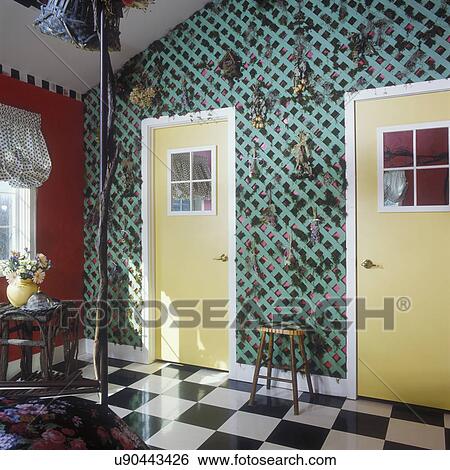 BEDROOM -Wall of green lattice and dried flowers, yellow doors, black and white checkered floor. red walls, partial balloon curtain, twig table, grapevine twisted around bed frame View Large Photo Image Stock Photograph - BEDROOM -Wall of green lattice and dried flowers, yellow doors, black and white checkered floor. red walls, partial balloon curtain, twig table, grapevine twisted around bed frame. Fotosearch