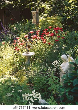 Stock Image - Birdhouse and small angel figurine in garden. Fotosearch