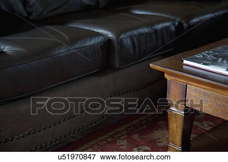 Stock Photo - Black leather sofa and wooden coffee table; Porterville; California; USA. Fotosearch