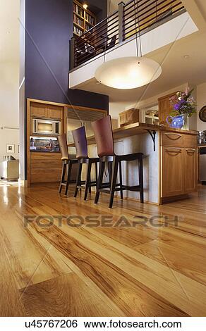 Stock Photograph - Chairs by kitchen island and hardwood flooring in house. Fotosearch