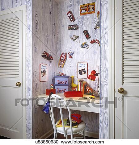 CHILDREN'S BEDROOM: Boy's room with white wood built-in desk. Blue and white faux wood wall paper. Red desk lamp, boxes. Tiny antique play cars hang above desk. View Large Photo Image Stock Image - CHILDREN'S BEDROOM: Boy's room with white wood built-in desk. Blue and white faux wood wall paper. Red desk lamp, boxes. Tiny antique play cars hang above desk.. Fotosearch