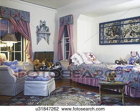 Stock Image - CHILDREN'S BEDROOM: Simple cottage, floral fabrics, window treatments, stuffed animals, hooked rug, wood floors, window frame with collage above bed, floral valance, checkered tie backs, toy chest, upholstered chair and ottoman,. Fotosearch