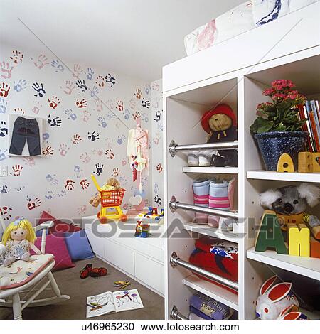 Stock Image - CHILDREN'S BEDROOM: Storage area for toys and gear wear. Wallpaper and bedding with hand and foot print design. Toys.. Fotosearch
