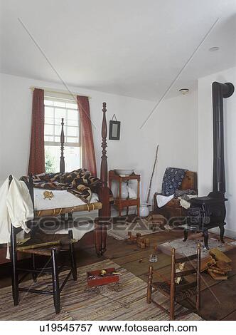 CHILDREN'S BEDROOMS: Boy's period colonial bedroom. Four poster bed, cast iron stove, ladder back chairs, wash stand. Wide plank floor. Antique toys. View Large Photo Image Stock Photo - CHILDREN'S BEDROOMS: Boy's period colonial bedroom. Four poster bed, cast iron stove, ladder back chairs, wash stand. Wide plank floor. Antique toys. . Fotosearch