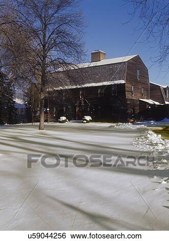 Stock Photograph - CHRISTMAS EXTERIORS: Dutch Colonial salt box style, weathered cedar, Christmas wreaths at every window and on the front doors, snowy, blue skies. Fotosearch