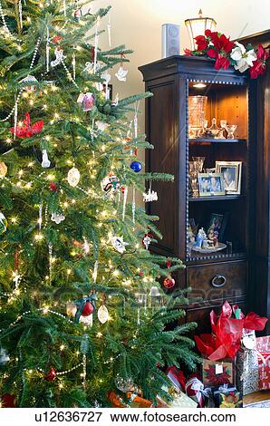 Stock Photo - Close-up of decorated lit Christmas tree and gift boxes. Fotosearch