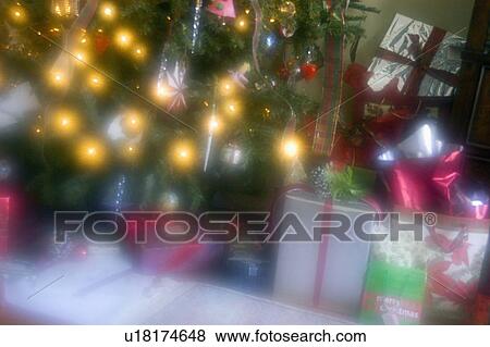 Stock Photo - Close-up of gift boxes with decorated Christmas tree. Fotosearch