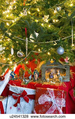 Stock Photo - Close-up of gift boxes with decorated lit Christmas tree. Fotosearch