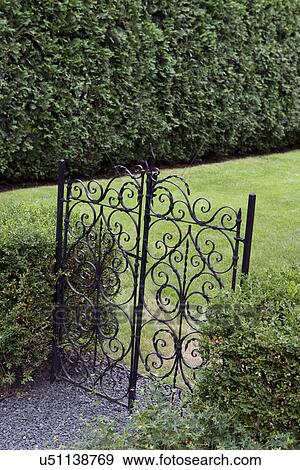 Stock Photo - Closed wrought iron gate with lawn. Fotosearch