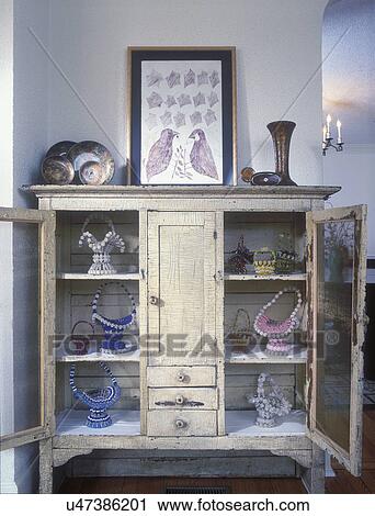COLLECTION -Beaded safety pin baskets in antique crackled cupboard, textured stucco walls, decoupage bowls and vase, primitive picture View Large Photo Image Stock Image - COLLECTION -Beaded safety pin baskets in antique crackled cupboard, textured stucco walls, decoupage bowls and vase, primitive picture . Fotosearch