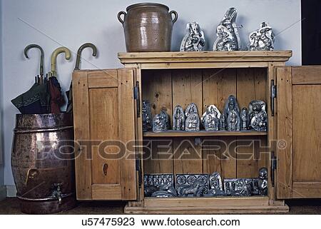 Stock Image - COLLECTION DISPLAY: Candy molds, weathered cabinet, copper water dispenser with umbrellas,. Fotosearch