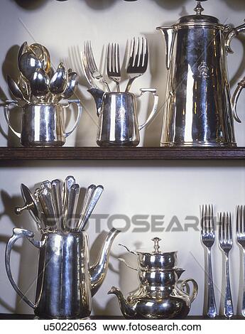 Stock Image - COLLECTION DISPLAY; Detail shot of shelves full of silver vintage Hotel silver service pieces and flatware. Fotosearch