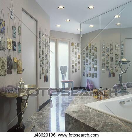 Stock Photograph - COLLECTION DISPLAYS: A metal mesh vintage purse collection on wall in Master bathroom. Brown veined marble, wall to wall mirror.. Fotosearch
