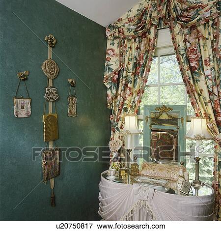 Stock Photo - COLLECTION DISPLAYS - Antique mesh purse collection displayed on sponged green wall, floral valance and curtains, dressing table, boudoir lamps. Fotosearch