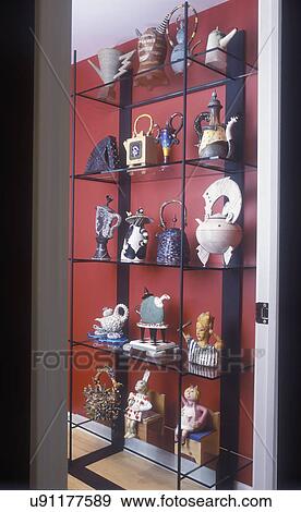 Stock Photo - COLLECTION DISPLAYS - Free standing shelving, glass and metal with art teapot collection, all unique by various artist. Whimsical themes, red walls. . Fotosearch