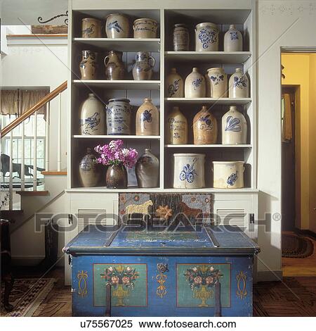 Stock Photography - COLLECTION DISPLAYS: Shelves with signed 19th Century Stoneware Collection, hooked rug, 1848 hand painted blue chest in foreground. . Fotosearch