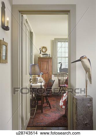 COLLECTION DISPLAYS - Wood carved water fowls and geese on display in hallway and family room. Early American antiques. Red area rug. View Large Photo Image Picture - COLLECTION DISPLAYS - Wood carved water fowls and geese on display in hallway and family room. Early American antiques. Red area rug. . Fotosearch