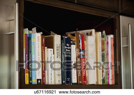 Stock Image - Collection of cookbooks on kitchen shelf; Irvine; California; USA. Fotosearch