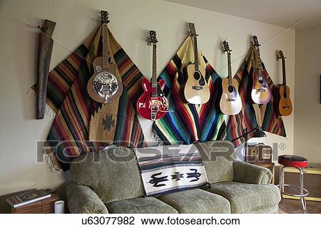 Stock Image - Collection of guitars hanging on wall in western themed living room; Porterville; California; USA. Fotosearch