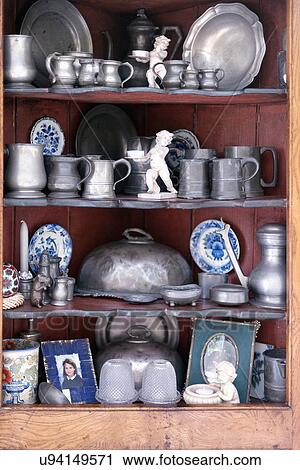 Stock Image - Collection of pewter cups and plates on shelves. Fotosearch