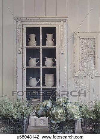 Stock Image - Collection of white pottery displayed in cabinet. Fotosearch