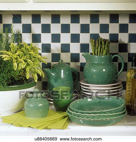 Stock Photo - COLLECTIONS - DISHES: Handmade pottery from Berea, KY. Dark green bowls, pitcher, sugar & creamer sit on a kitchen tile counter.. Fotosearch
