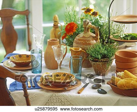 Stock Photography - COLLECTIONS - DISHES: Handmade Terra Cotta pottery creates a nice tablescape, rustic country look. Herb plants and flowers as a centerpiece, vintage white table linens, European pottery jugs, pine pitch pots, orange zinnias, stylist Pillar Simon. . Fotosearch